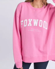 Pink sweatshirt with 'FOXWOOD' printed on it against a light gray background