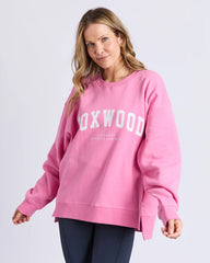 Woman wearing a pink 'Foxwood' sweatshirt on a light gray background