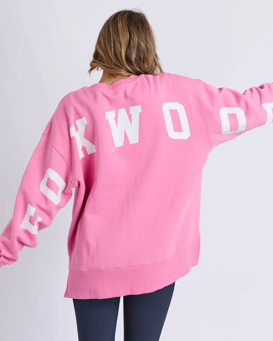 Person wearing a pink sweatshirt with 'FOXWOOD' printed on the back against a white background