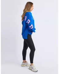 Woman wearing a blue oversized sweatshirt with pink text and black leggings on a white background