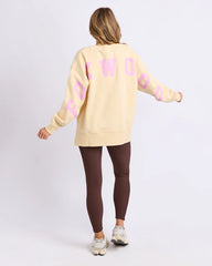 Woman wearing a yellow sweatshirt with pink text and brown leggings on a white background
