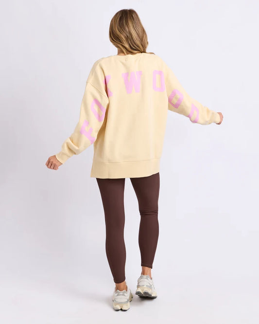 Woman wearing a yellow sweatshirt with pink text and brown leggings on a white background