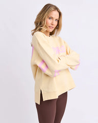 Woman wearing a light yellow sweater with pink accents on a white background