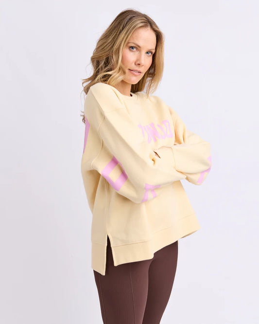Woman wearing a light yellow sweater with pink accents on a white background