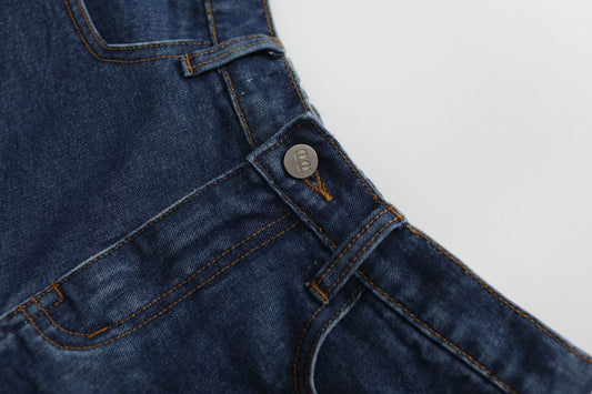 Close-up of blue denim overalls with a button on a light gray background
