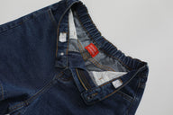 Close-up of a blue denim jacket with a red label on a light gray background
