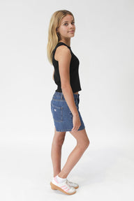 girl  wearing a black sleeveless top and denim shorts on a white background