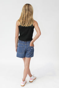 girl wearing a black tank top and blue shorts on a white background