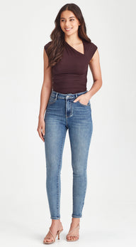 Woman wearing a brown top and blue jeans on a white background