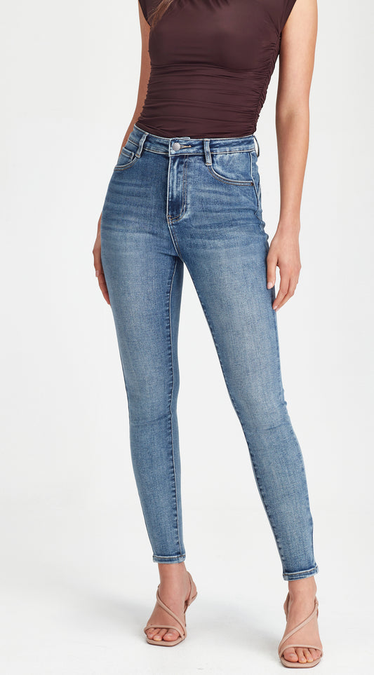 Person wearing blue jeans and a brown top on a white background