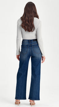 Person wearing blue jeans and a light gray top on a white background