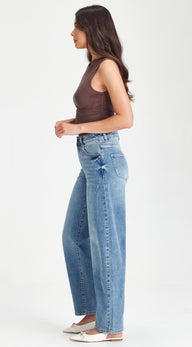 Woman wearing a brown tank top and blue jeans on a white background