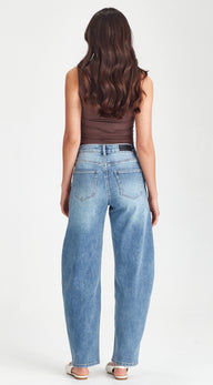 Woman wearing blue jeans and a brown top on a white background