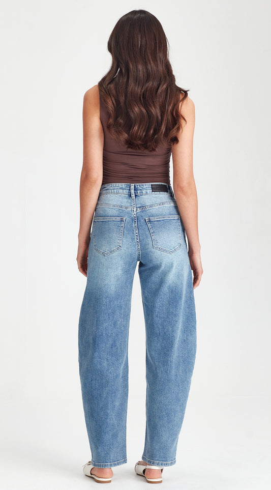 Woman wearing blue jeans and a brown top on a white background