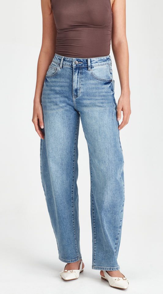 Person wearing blue jeans and a brown top on a white background