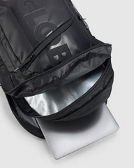 Black backpack with a laptop inside on a light gray background