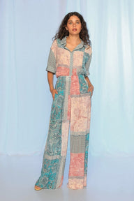 Woman wearing a patchwork jumpsuit against a light blue curtain background
