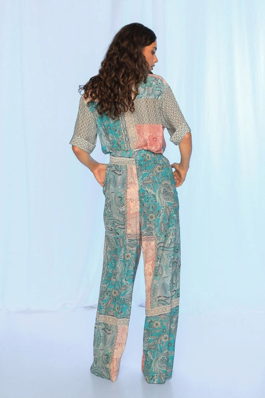 Woman wearing a patterned jumpsuit against a light blue background