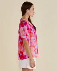 Woman wearing a colorful tie-dye shirt on a beige background
