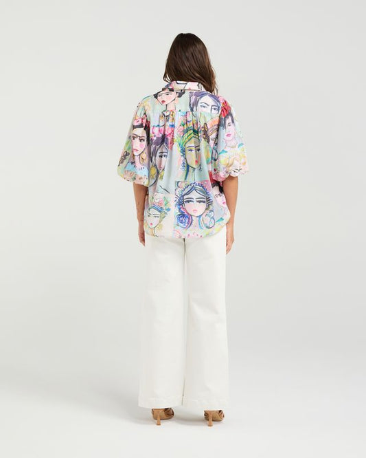 Woman wearing a colorful kimono-style shirt with face designs on a white background
