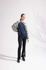 Woman wearing a navy sweater, black pants, and a floral jacket on a white background