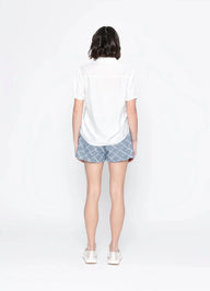 Person wearing a white t-shirt and patterned shorts on a white background