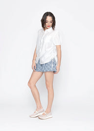 Woman wearing a white shirt and patterned shorts on a white background