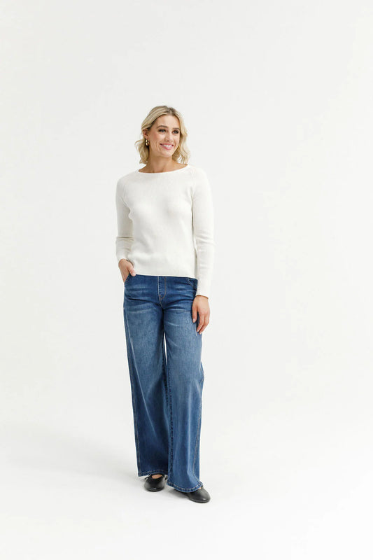 Woman wearing a white sweater and blue jeans on a white background