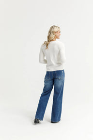 Woman wearing a white sweater and blue jeans on a white background