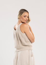Woman wearing a beige sleeveless top and long skirt on a white background
