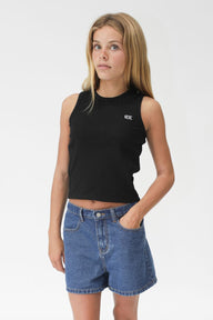Woman wearing a black sleeveless top and blue denim shorts on a white background