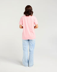A model viewed from behind wearing a light pink short-sleeve t-shirt and light blue wide-leg jeans, set against a plain light gray studio background.