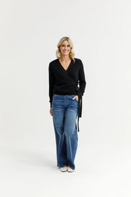 Woman wearing a black sweater and blue jeans on a white background