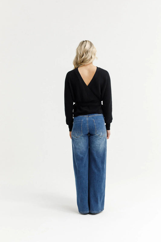 Person wearing a black top and blue jeans on a white background