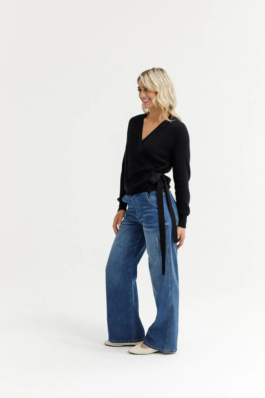 Woman wearing a black top and blue jeans on a white background