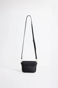A small black leather crossbody bag with a long shoulder strap and gold-tone hardware, photographed against a plain white studio background.