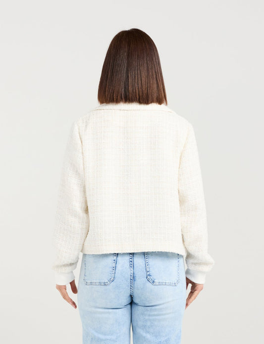 Person wearing a white sweater and light blue jeans on a plain background