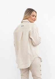 Person wearing a beige pinstripe outfit against a white background