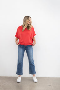 Woman wearing a pink knit and blue jeans on a white background