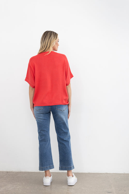 Woman wearing a pink knit and blue jeans on a white background