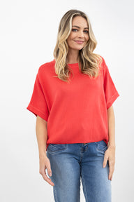 Woman wearing a pink knit and blue jeans on a white background