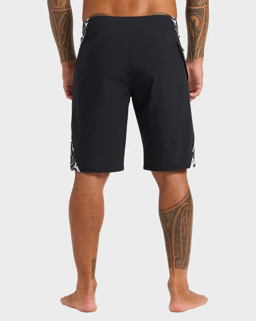 Person wearing black shorts with white patterns on a plain background
