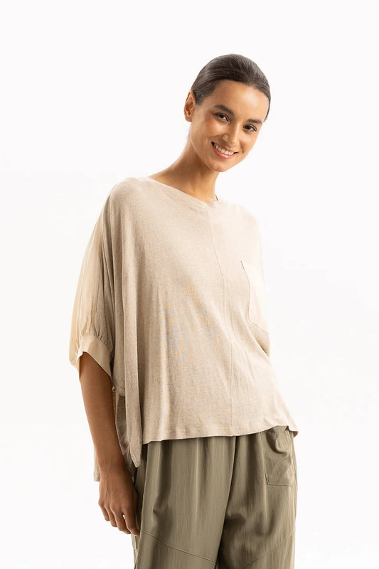 Woman wearing a beige top and green pants on a white background