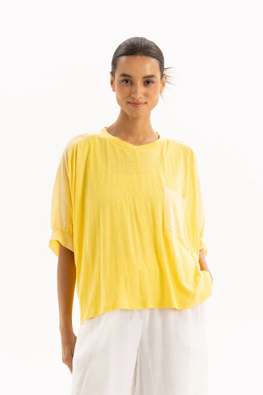 Woman wearing a yellow top and white pants on a white background