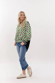 Woman wearing a green patterned sweater and blue jeans on a white background