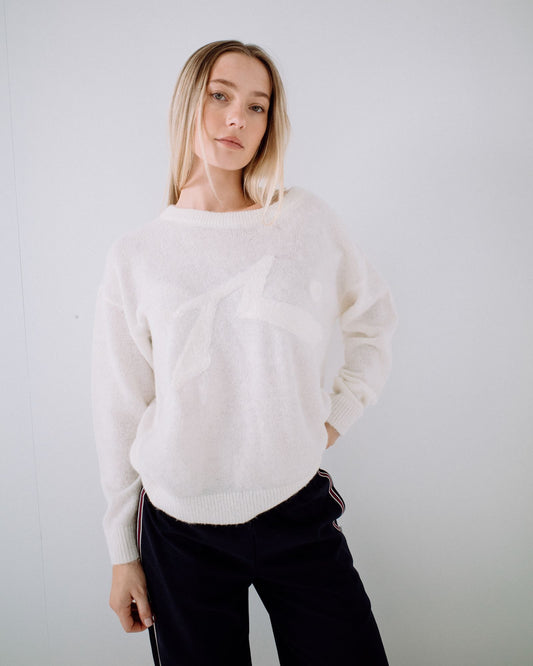 Woman wearing a white sweater against a plain background