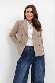 Woman wearing a beige checkered blazer and blue jeans on a white background
