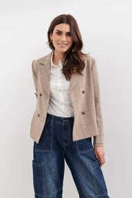 Woman wearing a beige blazer over a white shirt and blue jeans on a white background
