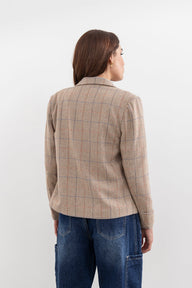 Person wearing a beige checkered blazer and blue jeans on a white background