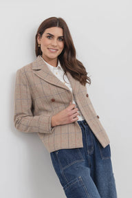 Woman wearing a beige checkered jacket and blue jeans against a white background